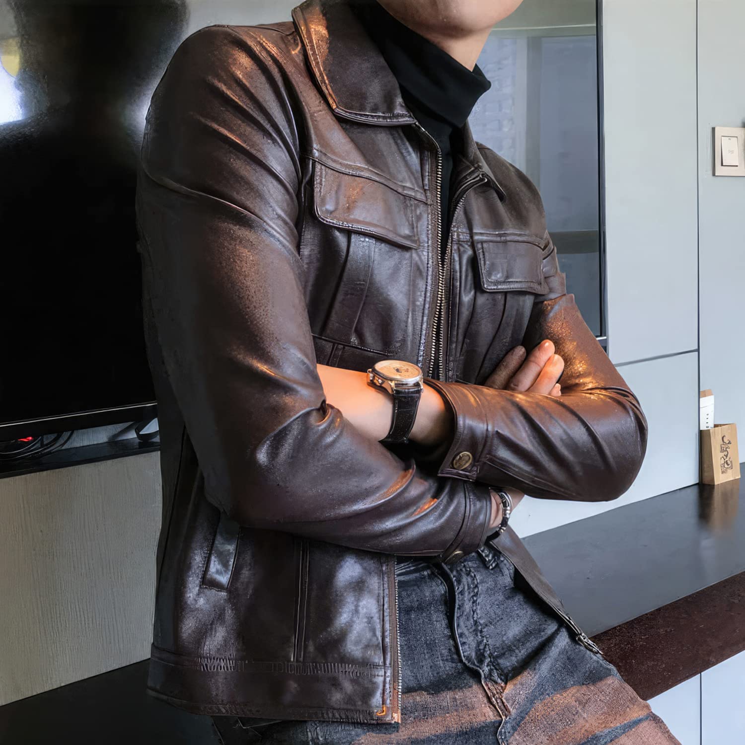 Person wearing a brown leather jacket with arms crossed indoors.