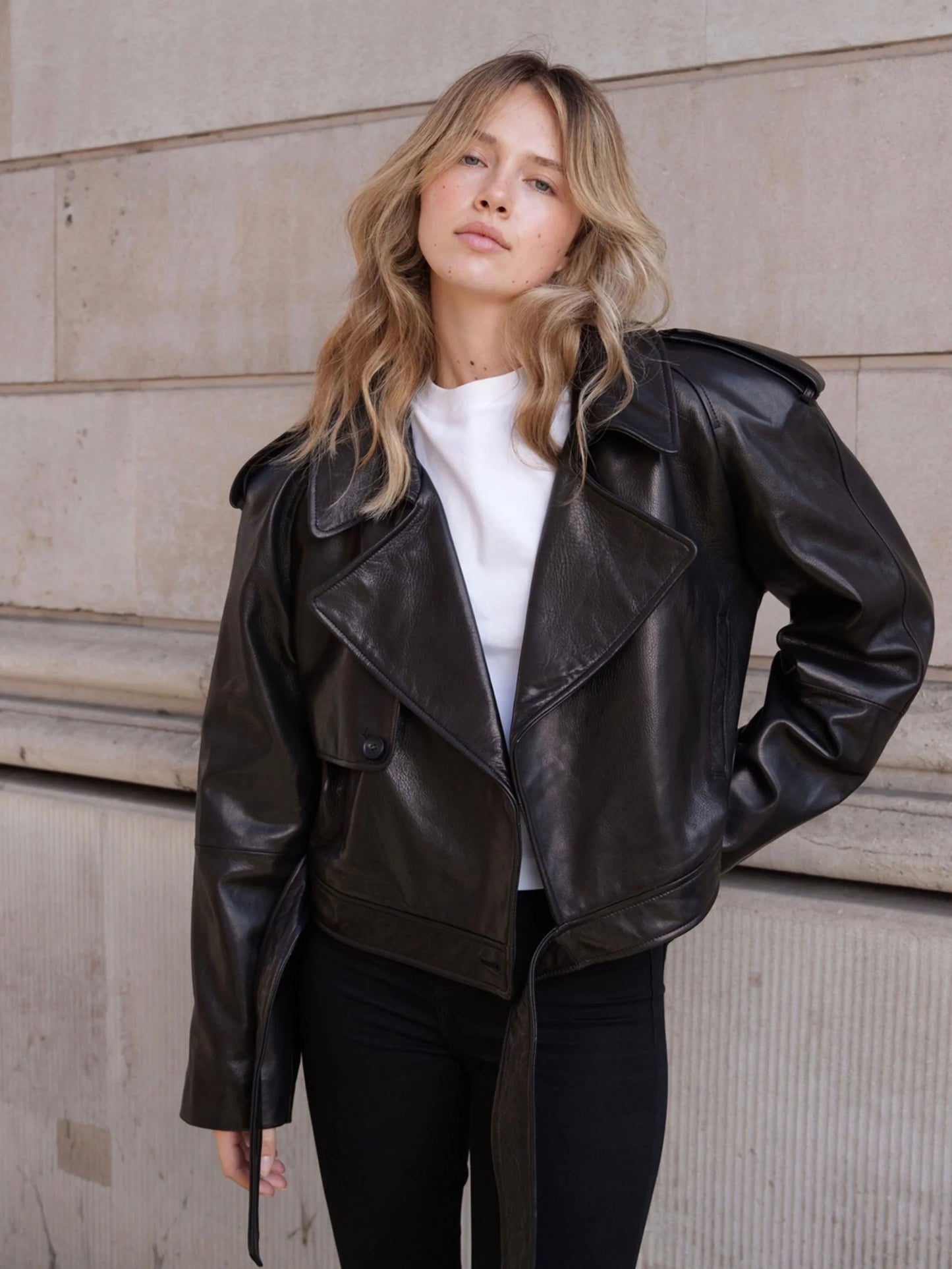 Woman wearing a black leather jacket against a neutral wall