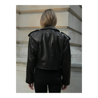 Person wearing a black leather jacket standing on a staircase.