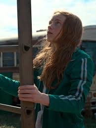Person wearing a green jacket with white stripes on a blurred outdoor background